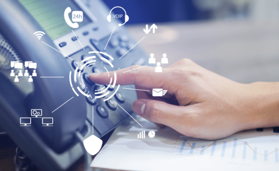 An employee of an SME about to press a button on a VoIP telephone which has saved their business money