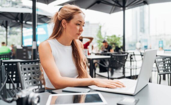 A remote worker using a laptop at an outdoor cafe, highlighting a common scenario where cybersecurity risks can be elevated due to public Wi-Fi and visibility.