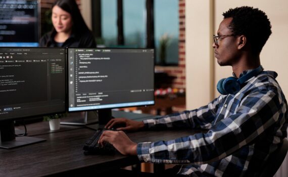 A man coding a computer who works for a cyber security company in the UK.
