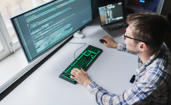 IT professional coding on dual monitors while working on cybersecurity solutions.
